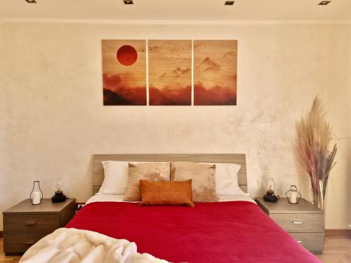 a bedroom with a red bed with three paintings on the wall at TraMonti Apartments in Poggio Picenze