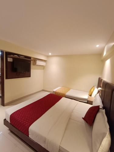 a bedroom with two beds and a flat screen tv at Hotel West INN-Near Mumbai International Airport in Mumbai