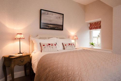 a bedroom with a large white bed with two lamps at West Lodge - Seasgair Lodges in Kincraig