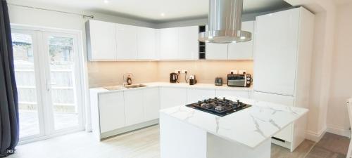 cocina con armarios blancos y encimera blanca en Green Garden in Northwest London en Londres