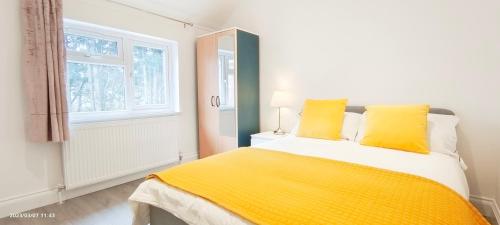 een slaapkamer met een bed met gele lakens en een raam bij Green Garden in Northwest London in Londen