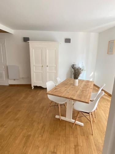 une salle à manger avec une table en bois et des chaises blanches dans l'établissement La Fontaine de Vinsobres, à Vinsobres