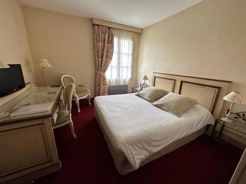 a hotel room with a bed and a desk and a window at Hôtel Domaine de l'Orangerie in Bonnat