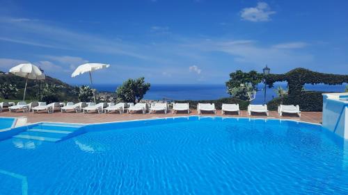 a swimming pool with chairs and the ocean in the background at Bilocale RESIDENCE MARASUSA in Parghelia