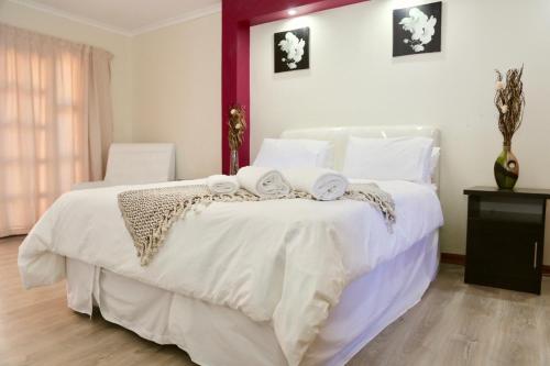 een slaapkamer met een wit bed en handdoeken bij Joy Guest House, Mabote in Maseru