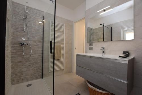 ein Bad mit einer Dusche, einem Waschbecken und einem Spiegel in der Unterkunft Casa Silù - Lago di Como in Colico