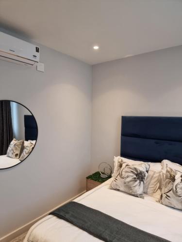 a bedroom with a bed with a blue headboard and a mirror at Zimbali Lakes Boulevard Suites in Ballito