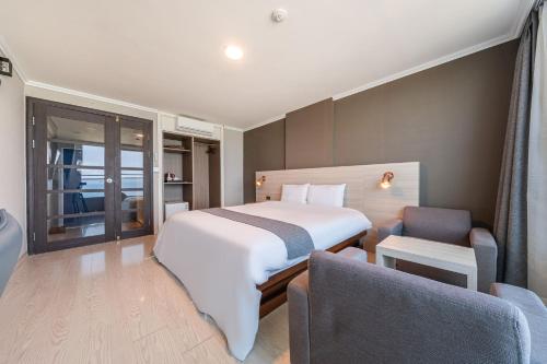 a bedroom with a bed and a chair in a room at Gyeongpo Soo Hotel in Gangneung
