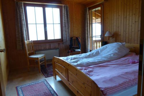 a bedroom with a bed and a chair and windows at Ferienhaus Bensel in Alvaneu