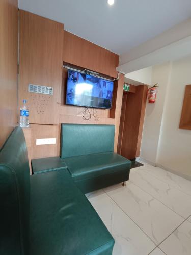 a waiting room with a green couch and a flat screen tv at Hotel West INN-Near Mumbai International Airport in Mumbai