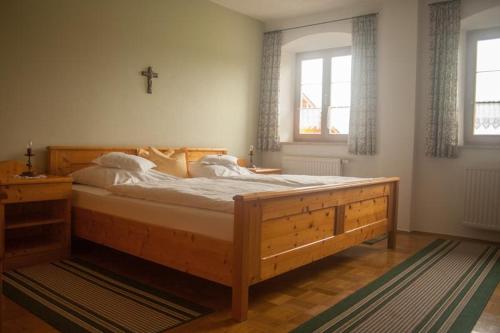 a large wooden bed in a bedroom with a cross on the wall at Gartlacher Hof in Eiselfing