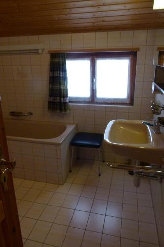 a bathroom with a tub and a sink at Ferienhaus Bensel in Alvaneu