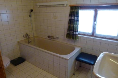a bathroom with a tub and a toilet and a sink at Ferienhaus Bensel in Alvaneu
