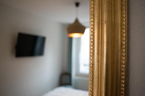 a gold mirror with a television in a room at Hôtel de la Béroche in Saint Aubin Sauges