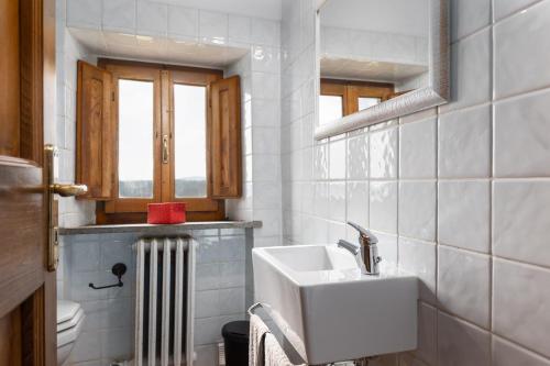 a white bathroom with a sink and a window at La Badia in Gambassi Terme