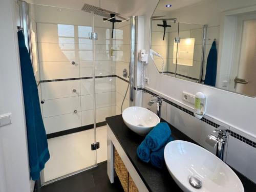 a bathroom with two sinks and a shower at Freie Sicht - Das Nordsee-Gesundheitshaus 1 in Dagebüll