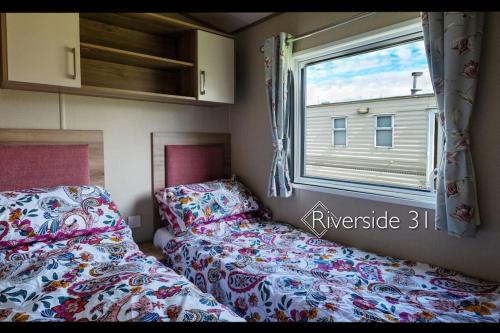 Habitación pequeña con 2 camas y ventana en 3 bedroom home on a Haven holiday park en Allhallows