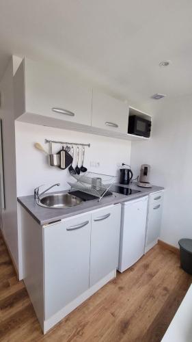 a kitchen with white cabinets and a sink at Le petit Château Avesnois - Studio en rez-de-chaussée in Avesnes-sur-Helpe