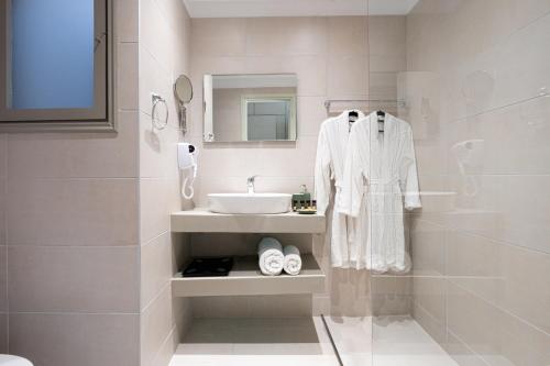 een witte badkamer met een wastafel en een spiegel bij RIVIERA HOTEL in Xylokastron