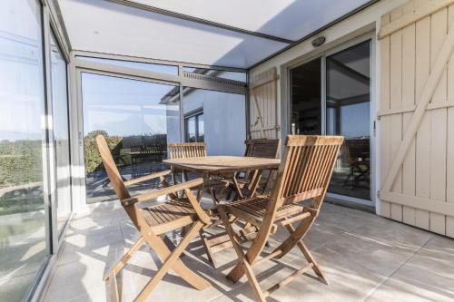 une table en bois et deux chaises sur un balcon dans l'établissement Jolie maison et sa véranda pour de belles vacances, à Saint-Philibert
