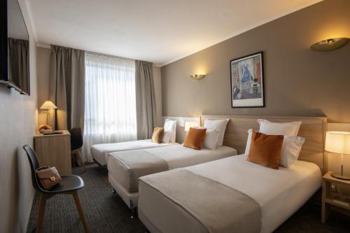 a hotel room with two beds and a window at Hotel Amarante Cannes in Cannes