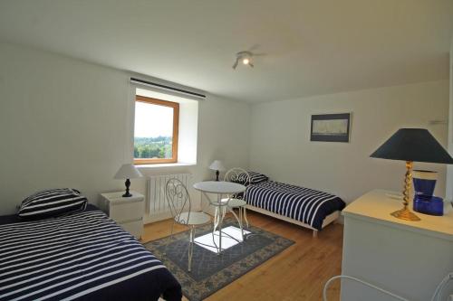 1 Schlafzimmer mit 2 Betten, einem Tisch und einem Fenster in der Unterkunft Chez le bayle in Condat-sur-Vienne