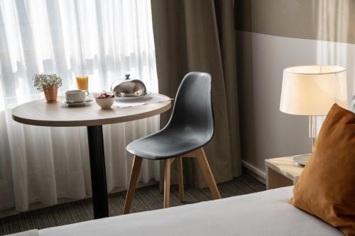 a table in a hotel room with a chair next to a window at Hotel Amarante Cannes in Cannes