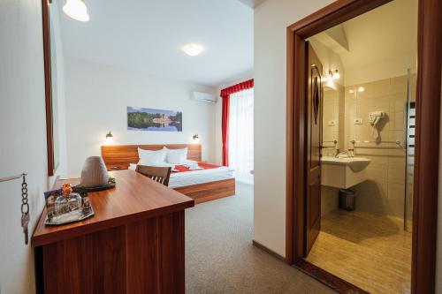 ソバタにあるPensiunea Comfortのベッド、デスク、バスルームが備わるホテルルームです。