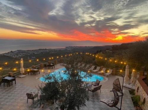 a view of a pool with a sunset in the background at KAZDAĞLARI ZEYTUNİHAN BUTİK OTEL in Edremit