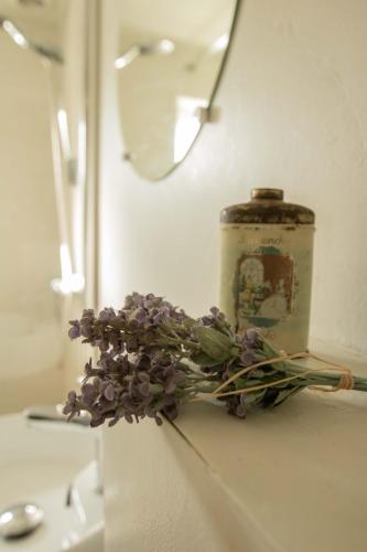 a candle and a bouquet of purple flowers on a counter at Chalet Ben in Broek in Benningbroek