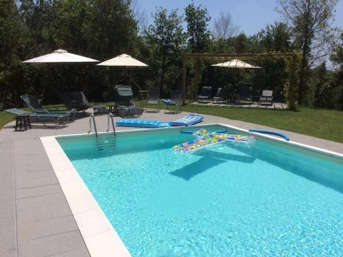 a swimming pool with chairs and umbrellas at Casa Lucchese al Borghetto in Collodi