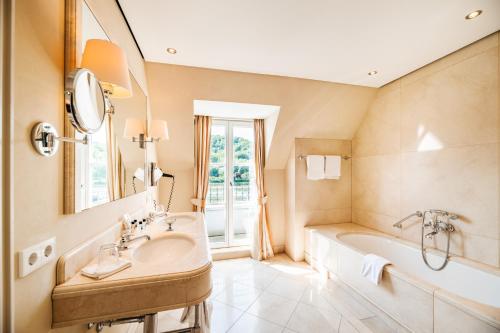 a bathroom with a sink and a tub and a mirror at Rheinhotel Schulz in Unkel