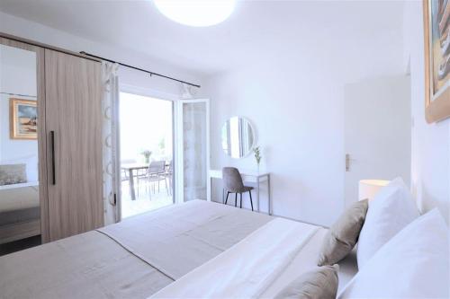 a white bedroom with a large bed and a balcony at Luxury beachfront villa with pool for two families in Trogir