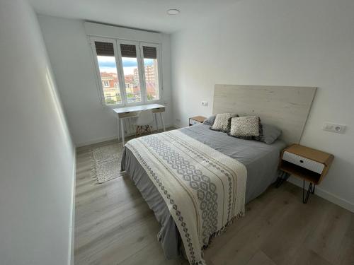 a white bedroom with a bed and two windows at Moderno, céntrico. Perfecto para familias. in Vitoria-Gasteiz