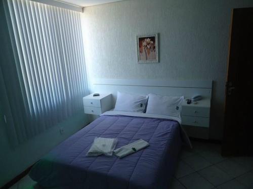 a bedroom with a bed with a purple blanket at Hotel Industrial Contagem in Contagem