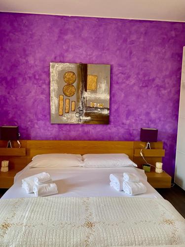 a bedroom with purple walls and a bed with towels at Villa Culla di Jana in Alghero