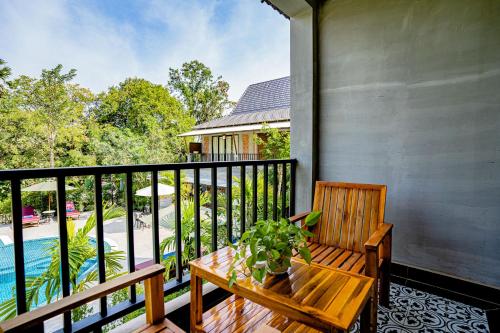a porch with a wooden bench and a potted plant at Kampot Sweet Boutique in Kampot