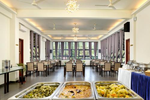 Una gran sala con mesas y sillas con comida en exhibición. en Fern Tree Resort, en Mananthavady