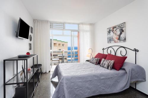 een slaapkamer met een bed met rode kussens en een balkon bij Home2Book Candemar Ocean View in Candelaria