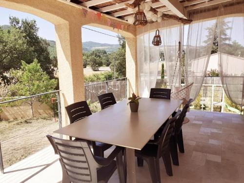 ein Esszimmer mit einem Tisch und Stühlen auf einer Terrasse in der Unterkunft Maison ensoleillée de plain-pied ouvert sur un jardin clôturé in Mallemoisson