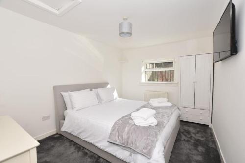 um quarto branco com uma cama e uma televisão de ecrã plano em 3 Bedroom Apartment in a Quiet Location em Airdrie