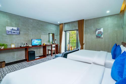 a hotel room with two beds and a television at Kampot Sweet Boutique in Kampot