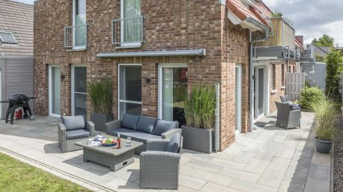 a patio with chairs and a table in front of a brick building at Ferienwohnung Rudi s Huus, FeWo Vermittlung Nordsee in Langendamm