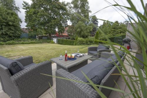 a patio with wicker chairs and a table in a yard at Ferienwohnung Rudi s Huus, FeWo Vermittlung Nordsee in Langendamm