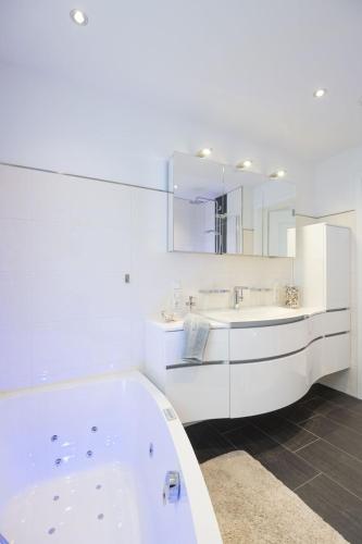 a white bathroom with a tub and a mirror at Ferienwohnung Rudi s Huus, FeWo Vermittlung Nordsee in Langendamm