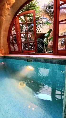 a swimming pool in a house with a window at Il Mithna farmhouse with indoor heated jacuzzi pool in Għarb