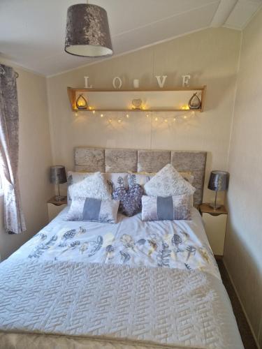 een slaapkamer met een groot wit bed met kussens bij 3 bedroom Caravan Craigtara in Ayr