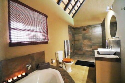 y baño con bañera, aseo y lavamanos. en Leopard Rock Guest Lodge, en Mica