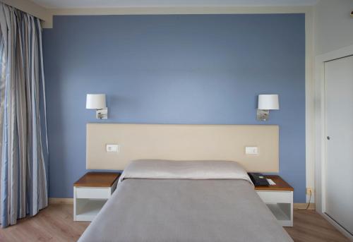 a bedroom with a bed with blue walls and two tables at Seth Agamenon in Es Castell