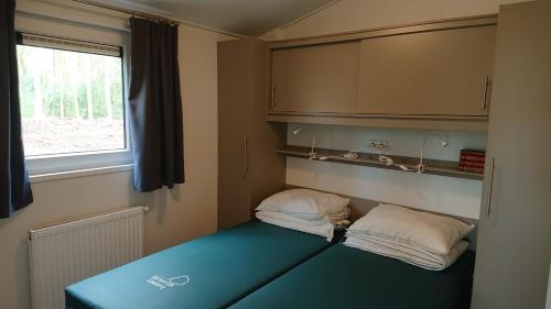 een kamer met een bed met 2 kussens en een raam bij Chalet Camping Natuurlijk Limburg in Remersdaal